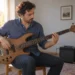 Dört telli bas gitarda parmak çalışması yapan yetişkin müzisyen.