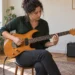 Altı telli elektro gitarda akor ve pena çalışması yapan yetişkin müzisyen.