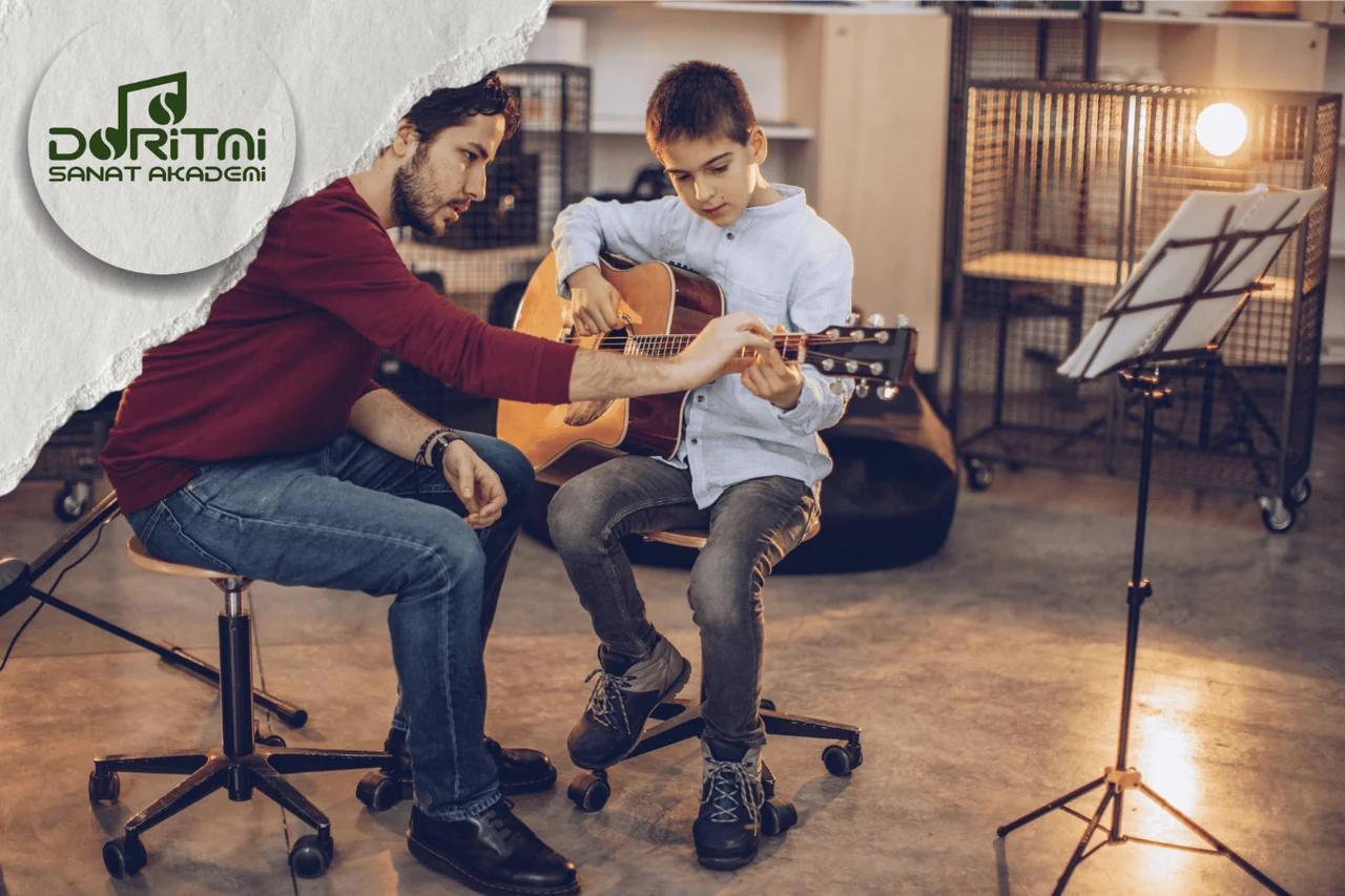 Gitar çalan çocuğun el konumuna rehberlik eden yetişkin.