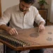 Kanun tellerinde iki el ve parmak mızraplarıyla çalışan yetişkin müzisyen.