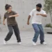 Açık avluda birlikte street dance adımları çalışan iki yetişkin.